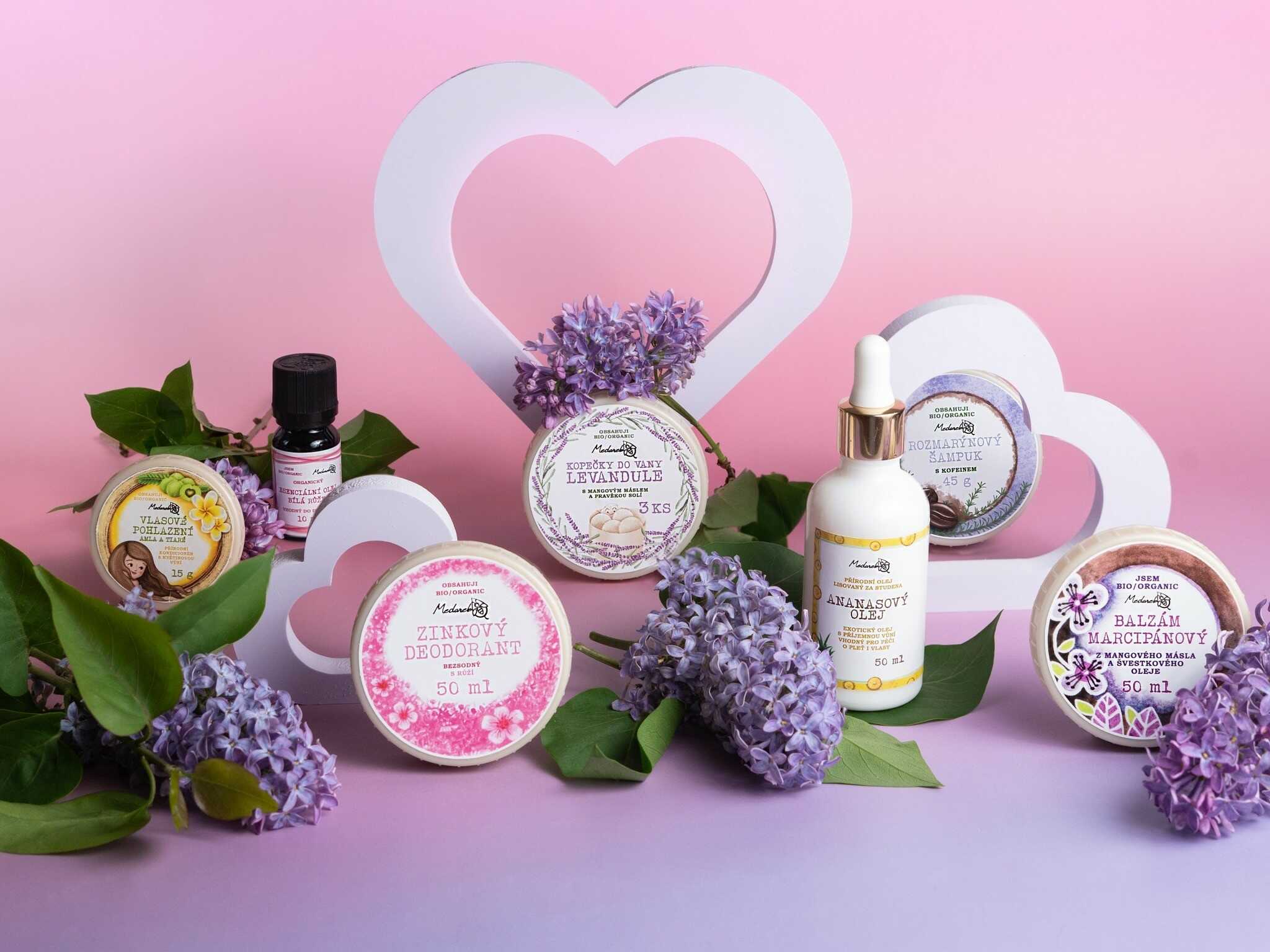 Medarek natural skincare products arranged with lilac flowers and heart cutouts on a pink-purple backdrop